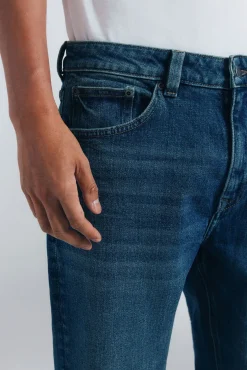 Calça jeans reta com lavagem escura e tingimento excessivo